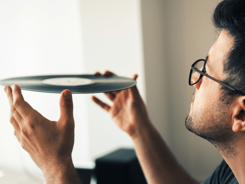 Man holding up a vinyl record and inspecting it