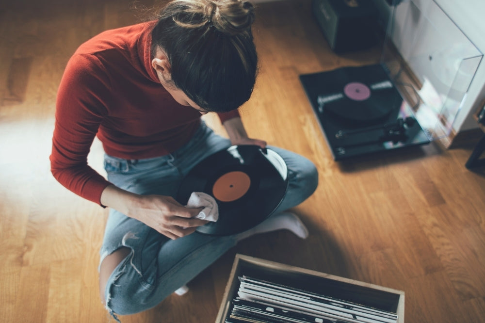 Lady cleaning a vinyl record with a cloth