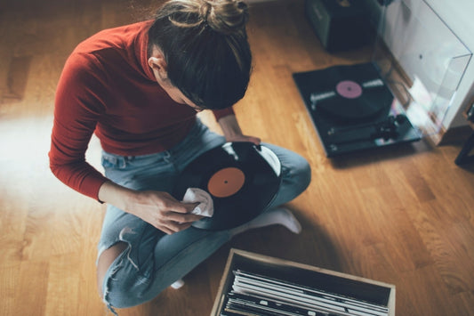Lady cleaning a vinyl record with a cloth